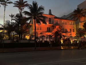 Photograph of a Spanish style masion at dusk with red floodlighting and palm trees